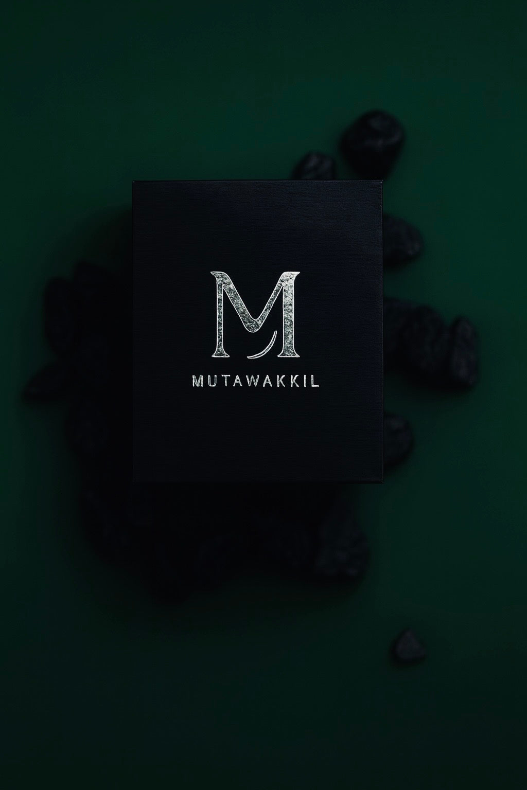 Luxury black Mutawakkil jewelry box with silver embossed logo on dark green background.