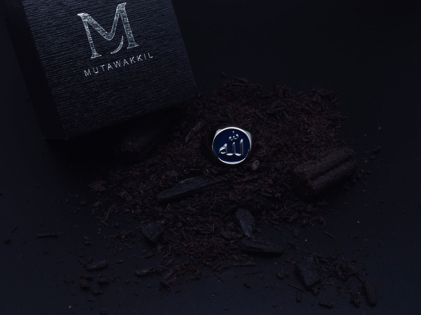 Mutawakkil Sabr blue Islamic ring engraved with Allah in Arabic calligraphy, symbol of patience, beside luxury black box.